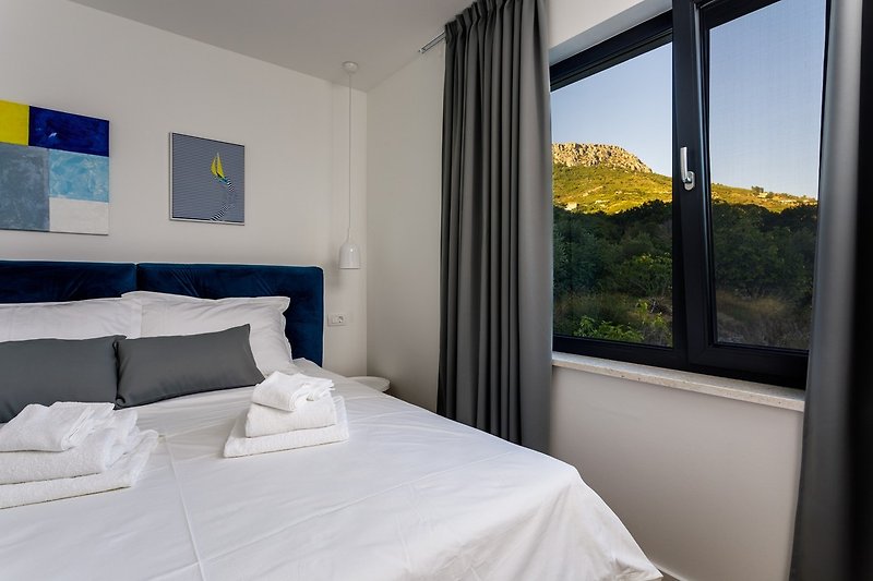Bedroom No1 with a king size bed 180cm x 200cm, air conditioner, a TV and views on hills.