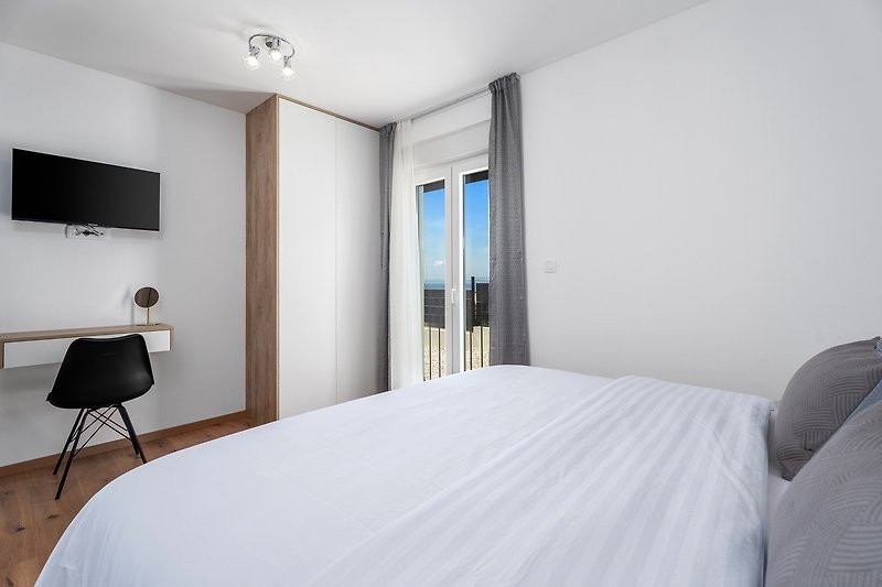 Schlafzimmer Nr. 1 mit Fernseher und Klimaanlage, mit Blick auf die umliegenden Olivenbäume.