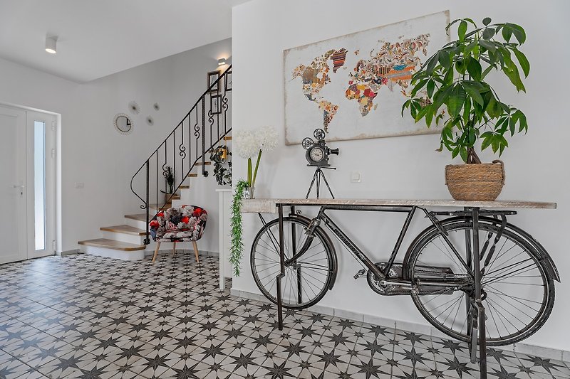 The hallway is a feast for the eyes, with paintings, bicycle sculptures, and vases adorning the walls and shelves.