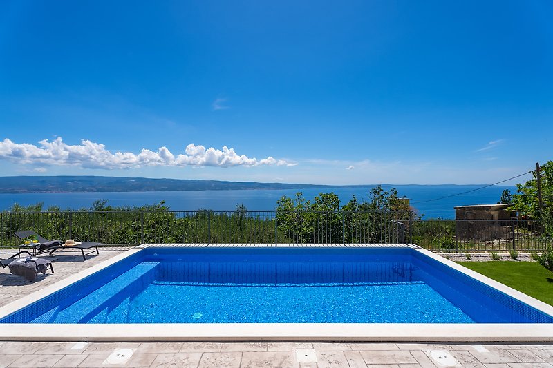 Privater Pool mit Palmen, Liegestühlen und Blick auf den Himmel.