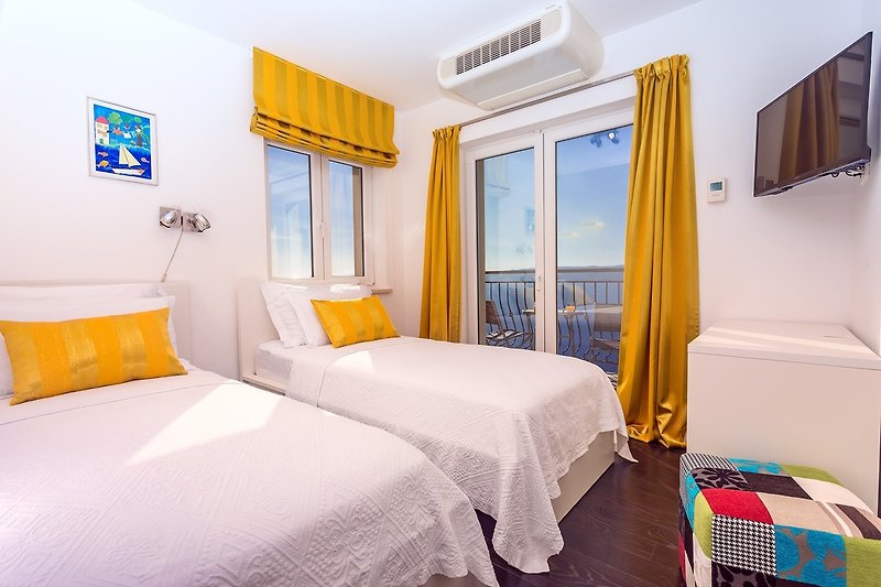 Sypialnia nr 3 z dwoma pojedynczymi łóżkami o wymiarach 90 cm x 200 cm, balkonem, klimatyzacją i telewizorem.
