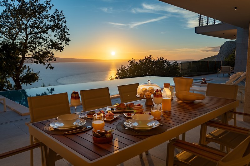 A charming outdoor dining area with comfortable furniture and a view of the ocean.
