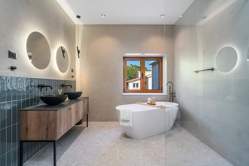 En-suite bathroom with a self-standing bathtub and a shower, a double sink, a toilet.