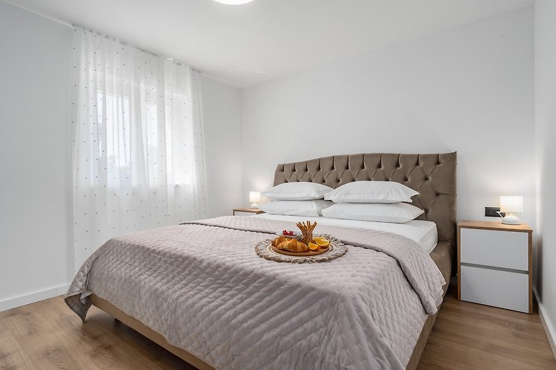 Schlafzimmer Nr. 2 (13,3 m2) mit einem Doppelbett 180 cm x 200 cm, Klimaanlage, einem Fernseher und Blick auf die natür