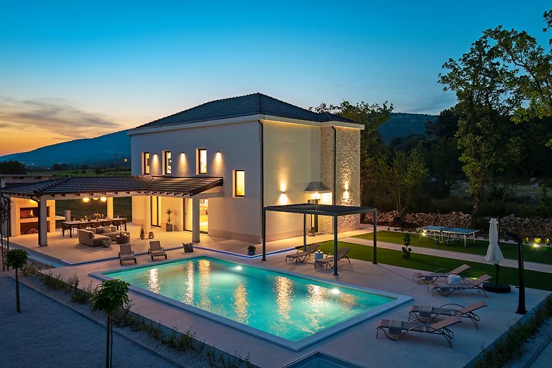 Villa mit Pool, Innenhof und nächtlicher Beleuchtung.