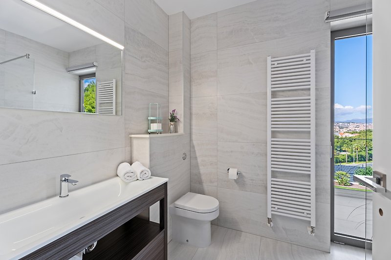 Modernes Badezimmer mit lila Waschbecken, Dusche und Fenster.