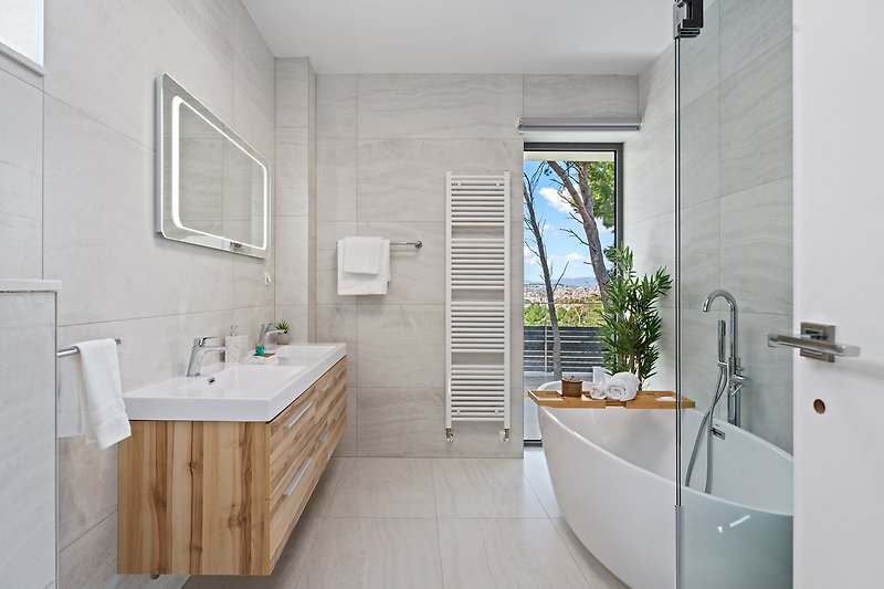 Modernes Badezimmer mit Badewanne, Spiegel und Pflanze.