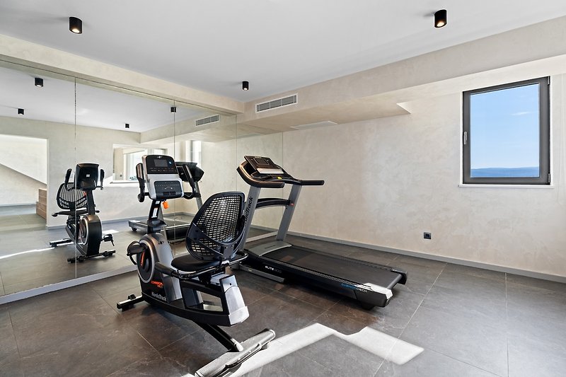 Ein Fitnessbereich bietet einen Heimtrainer und ein Laufband, einen Fernseher und eine Klimaanlage