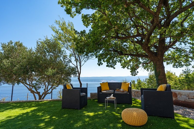 Escape to a peaceful oasis with lush vegetation, a serene water view, and comfortable outdoor furniture.