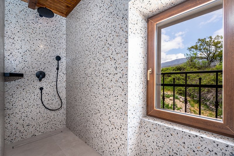 En-suite Badezimmer mit Dusche und Fenster mit Blick auf die umliegende Natur