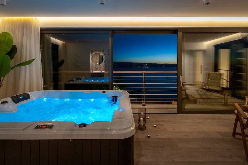 A luxurious indoor oasis with a jacuzzi, elegant interior design, and a stunning view of the azure water.
