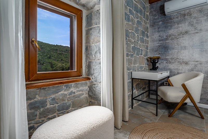 Ein stilvoller offener Küchen- und Wohnbereich mit einem Fenster mit Blick in die unberührte Natur.