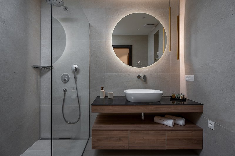 A modern bathroom with a stylish mirror, elegant fixtures, and beautiful flooring.