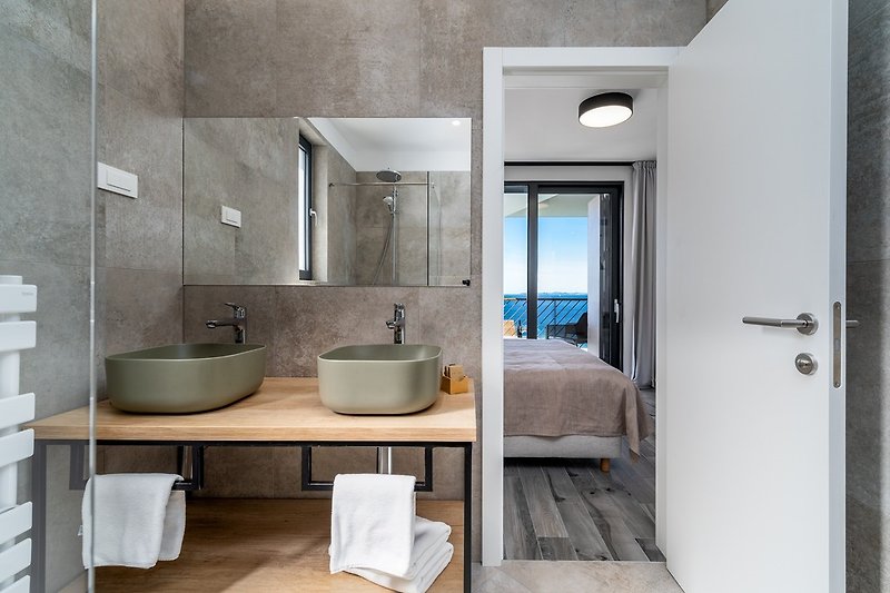 An en-suite bathroom with a shower, 2 sinks, and a toilet