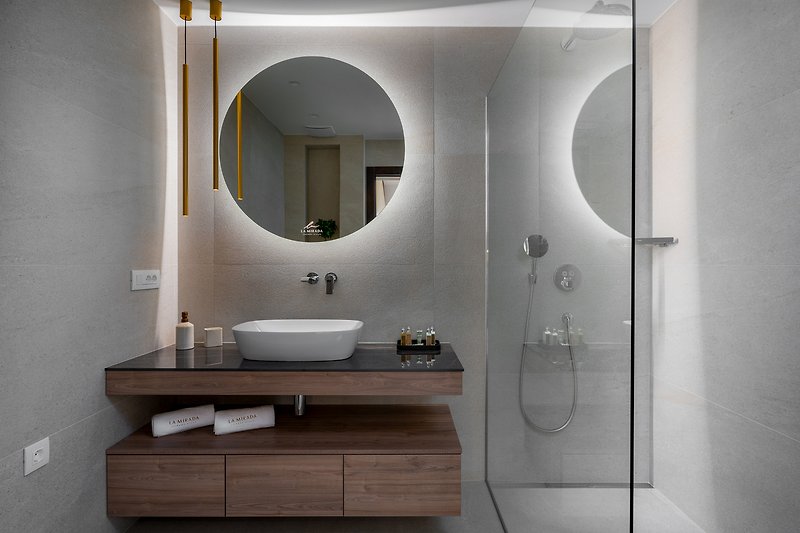 A modern bathroom with a stylish mirror, comfortable fixtures, and elegant flooring.
