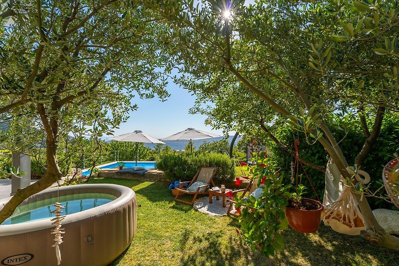 Rasenfläche mit Softub Whirpool, eine Lounge-Ecke unter den Olivenbäumen als perfekter Ort zum Schilfen und Entspannen