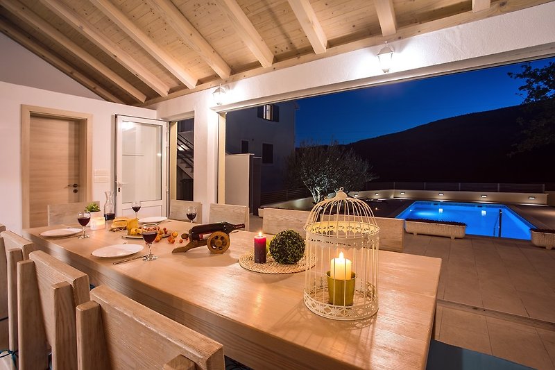 Dining area next to the fully equipped kitchen with view on the great lighted pool area