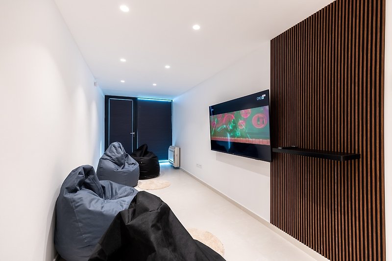 There is also a Media room with 4 lazy bags, flat screen TV, a PlayStation 5, and glass doors to artificial grass