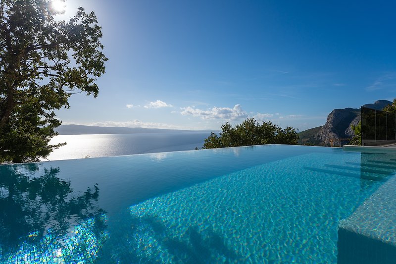 A breathtaking coastal landscape with a sparkling swimming pool and lush greenery.