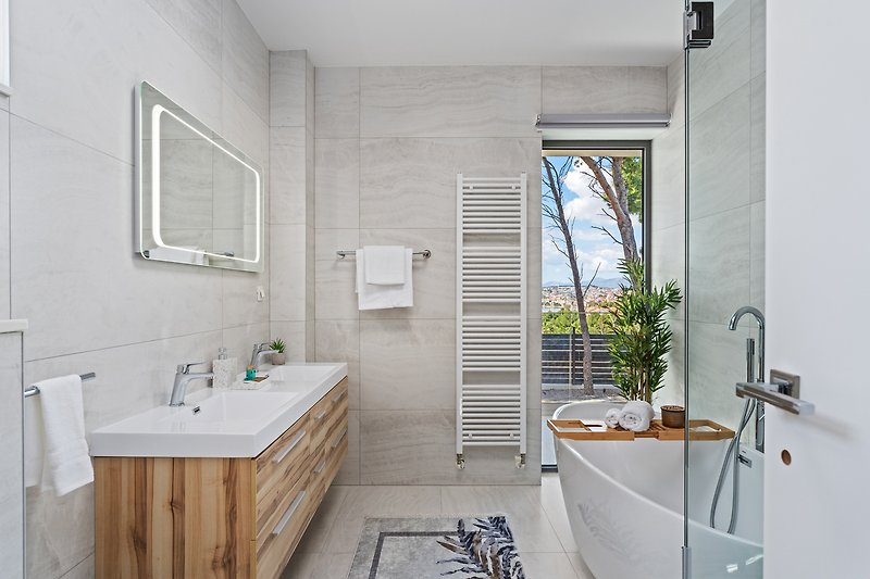 Modernes Badezimmer mit Spiegel, Waschbecken und Pflanze.