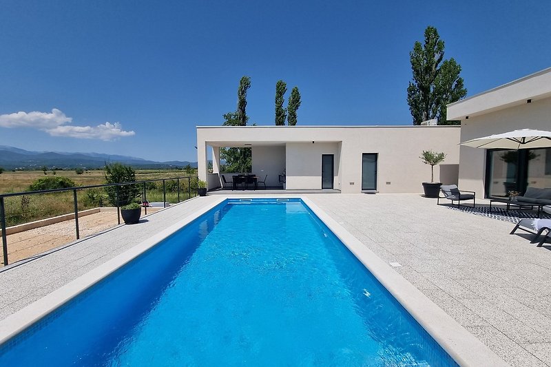 Villa mit Pool, Gartenblick und stilvollen Outdoor-Möbeln.