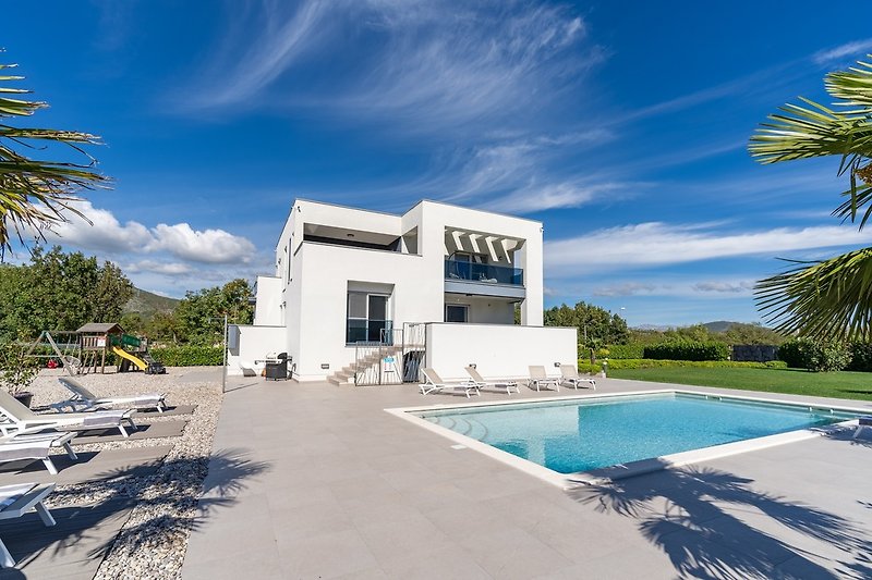 Private, heated pool with spacious sun deck in front of the villa with 10 sun chairs