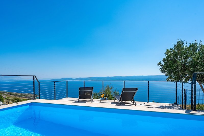 Relax by the pool in this stunning seaside resort with beautiful landscape and outdoor furniture.