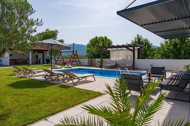 Relax by the pool in this oasis with stunning views and comfortable outdoor furniture.