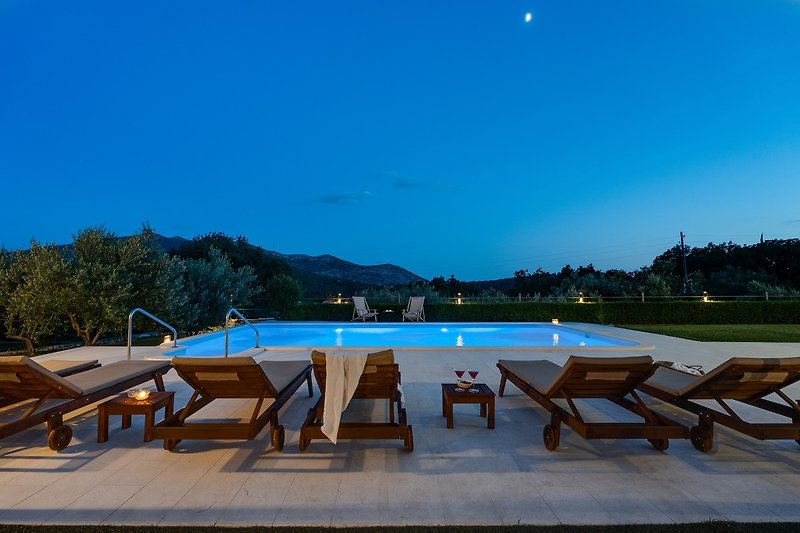 Relax by the poolside with stunning views of the azure sky and outdoor furniture.