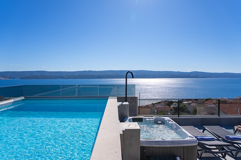 Luxusvilla am Wasser mit Pool, Sonnenliegen und Meerblick.