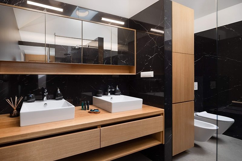 An en-suite bathroom with a bathtub and a shower, a double sink, a toilet, and a bidet.