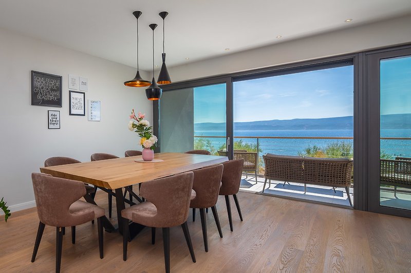Luxuriously furnished living and dining area with glass wall on sea side, first floor