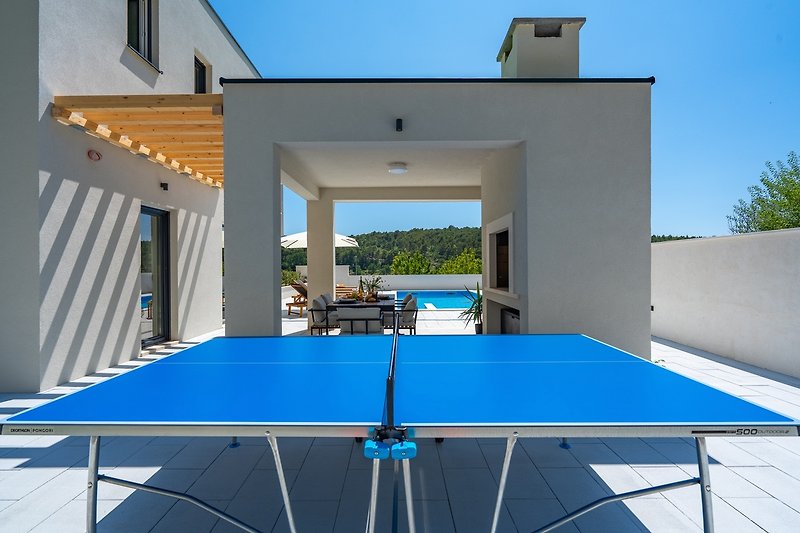 Rent this stunning property with outdoor furniture, ping pong table, and a beautiful view of the azure sky.