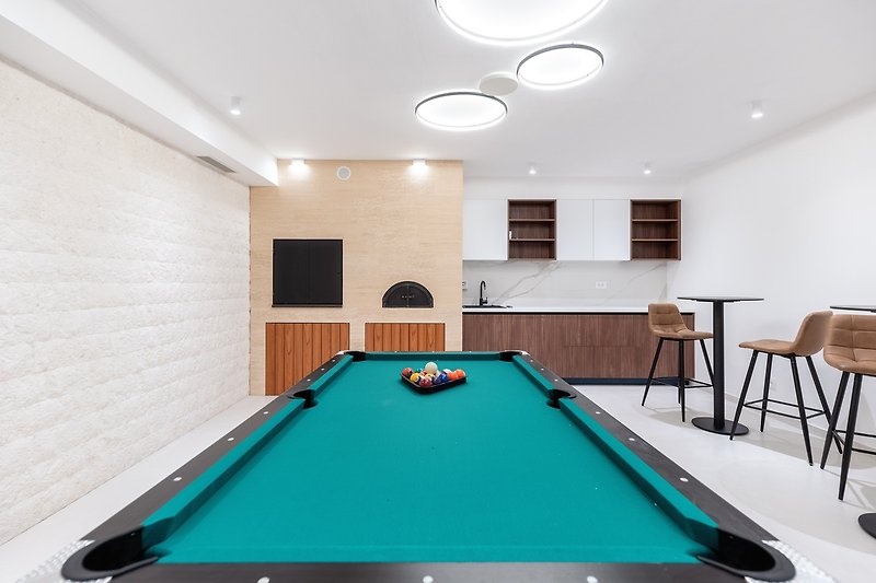 Next to it is a fun zone with a Pool table (Billiards), a TV, two bar tables, a kitchenette, and a barbecue area