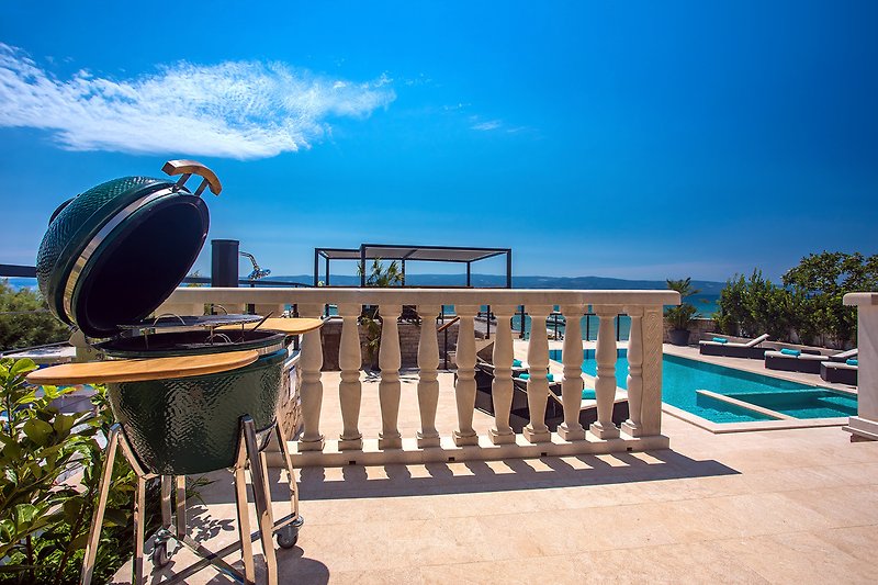 Moderne grill naast de buiten eetruimte met uitzicht op het zwembad en de zee