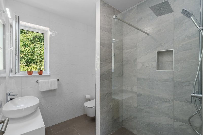 Rent this modern bathroom with a sleek sink, glass shower, and stylish fixtures.
