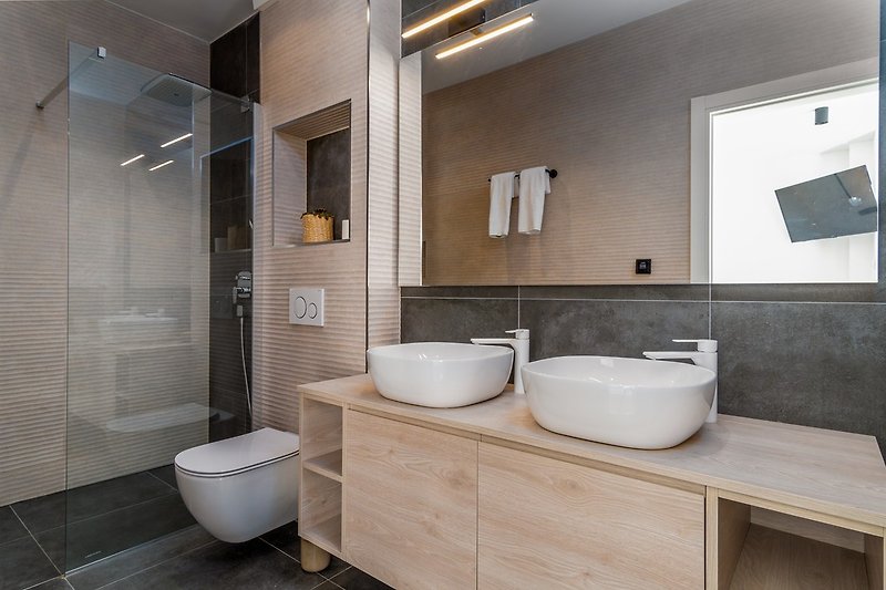 An en-suite bathroom with a shower, a double sink, and a toilet