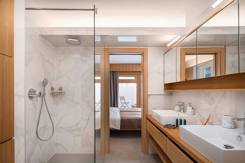 An en-suite bathroom with a shower, a double sink, a toilet, and a bidet.