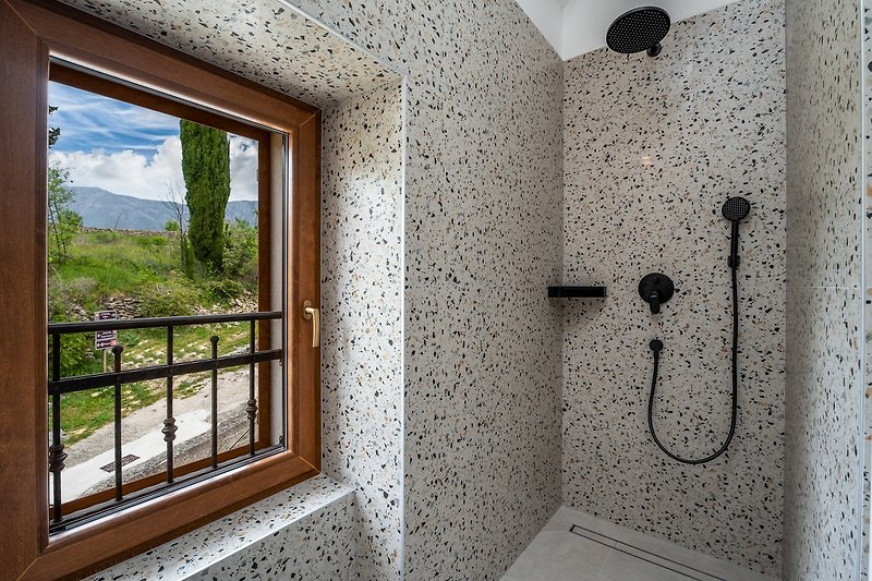 En-suite Badezimmer mit Dusche und Fenster mit Blick auf die umliegende Natur