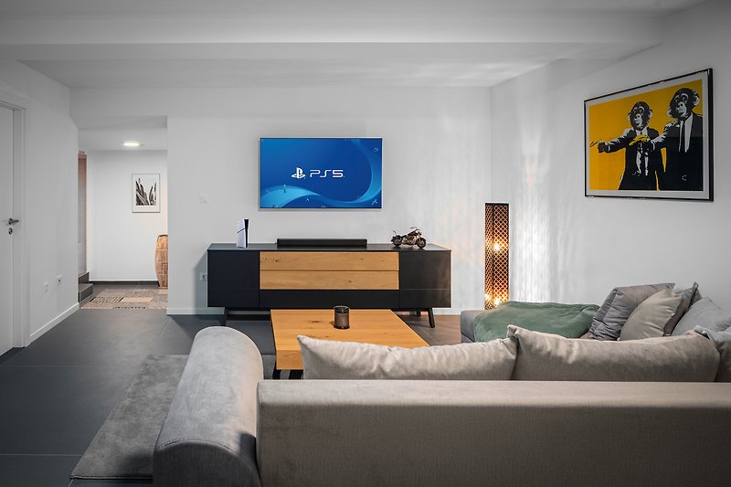 Medienraum mit Sofa, PlayStation 5, Fernseher und einigen Spielen für noch mehr Spaß