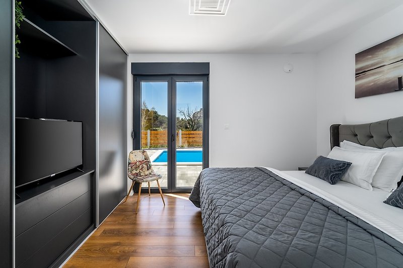 Schlafzimmer Nr. 1 mit Kingsize-Bett 180 cm x 200 cm, Bad mit Dusche, Fernseher, Klimaanlage und Ausgang zum Poolbereich