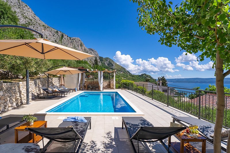 Bergresort mit Pool, Sonnenliegen und Palmen, ideal zum Entspannen.