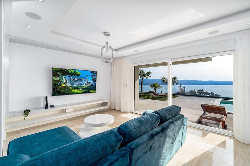 Living room consists a comfy sofas, flat screen smart TV, PS5, A/C