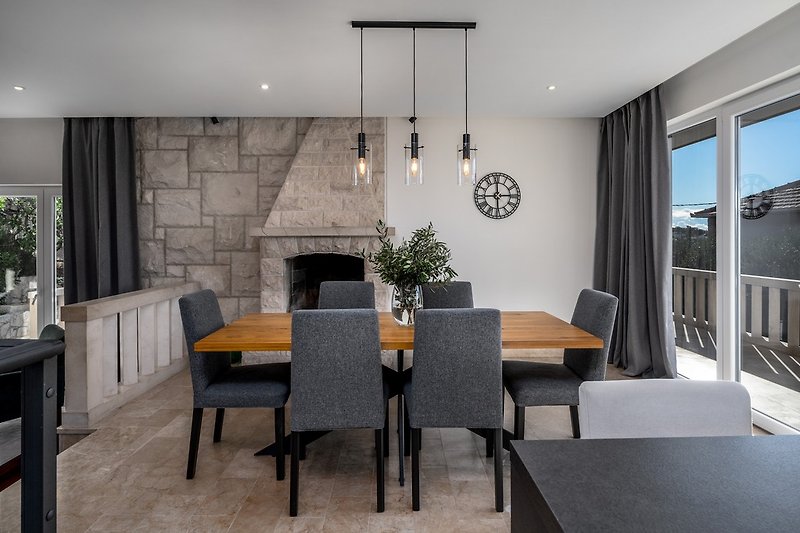 A dining area with a fireplace and a terrace with sea views connected to a terrace with outdoor dining area.