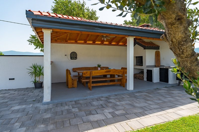 The outdoor area offers a covered outdoor dining area with the traditional barbecue