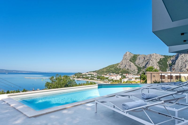 a sun deck area with 6 deck chairs overviewing town Omiš, sea and mountains