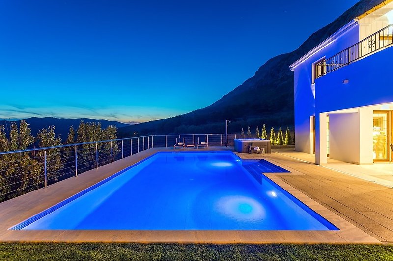 A night view on private swimming pool, Jacuzzi and covered outdoor dining area.