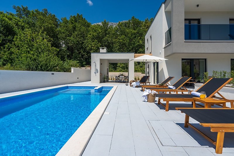 Stunning property with a swimming pool, blue sky, and outdoor furniture.