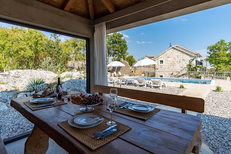 A fully equipped summer kitchen with traditional barbecue area, dining tables, a TV and a separate toilet.