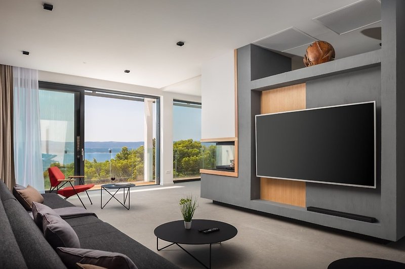 Der Wohnbereich dieses hellen und luftigen Raumes bietet einen Flachbild-TV, eine PS4, einen Kamin, zwei bequeme Sofas